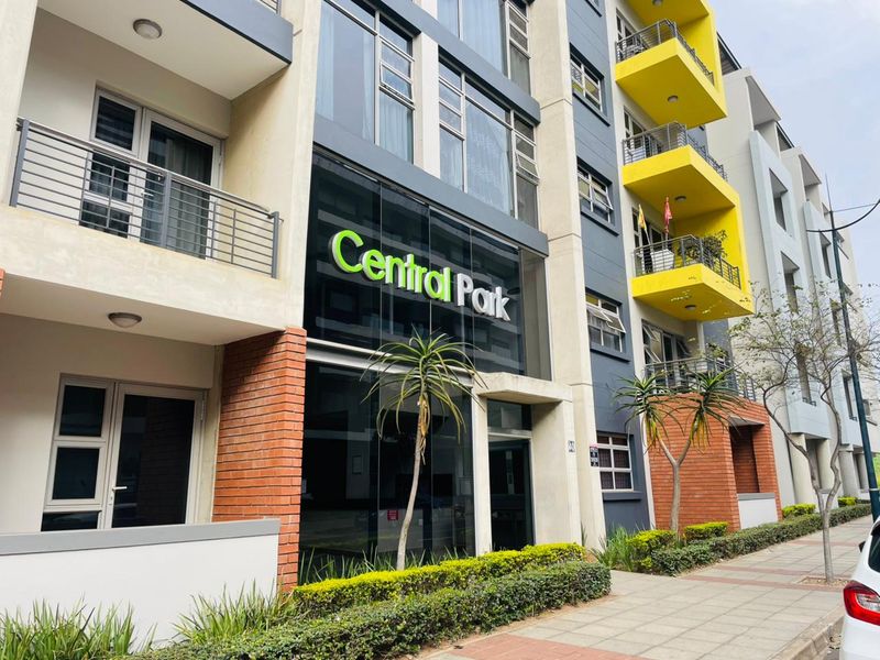 Exterior view of the Central Park apartment complex featuring a modern facade with brick accents, glass elements, and private balconies.