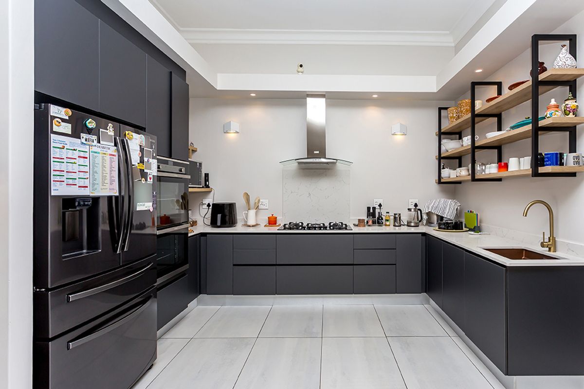 Modern U-shaped kitchen featuring dark matte cabinetry, stone countertops, integrated stainless steel oven, gas hob, extractor fan, and open timber shelving.