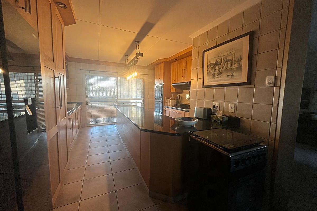 A functional kitchen featuring wooden cabinetry, granite countertops, tiled backsplash, and direct access to an outdoor area through sliding glass doors.