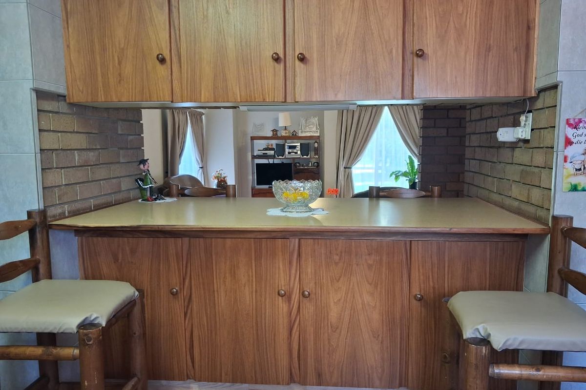 A kitchen pass-through area featuring wood-finish cabinetry, a laminate countertop, and exposed brick detailing, connecting to the adjacent living space.