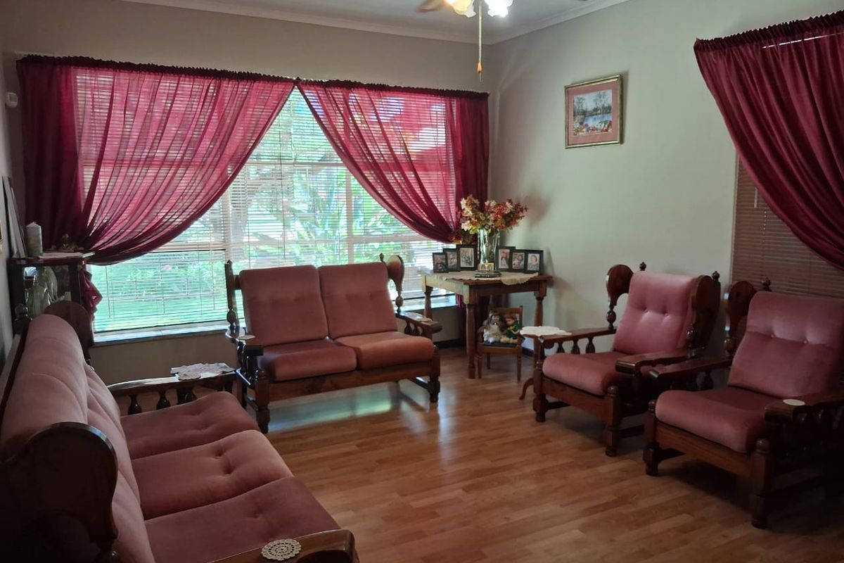 A comfortable living room featuring laminate flooring, a ceiling fan, and large windows that provide natural light.