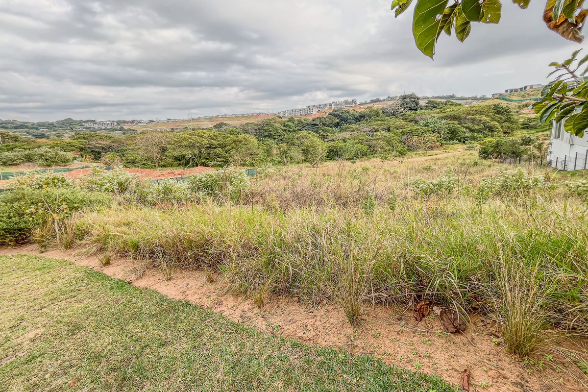 A wide-angle view of the vacant residential land, showcasing the natural landscape, surrounding vegetation, and sloped terrain of the property.