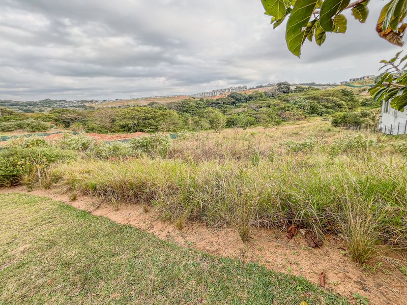 A wide-angle view of the vacant residential land, showcasing the natural landscape, surrounding vegetation, and sloped terrain of the property.