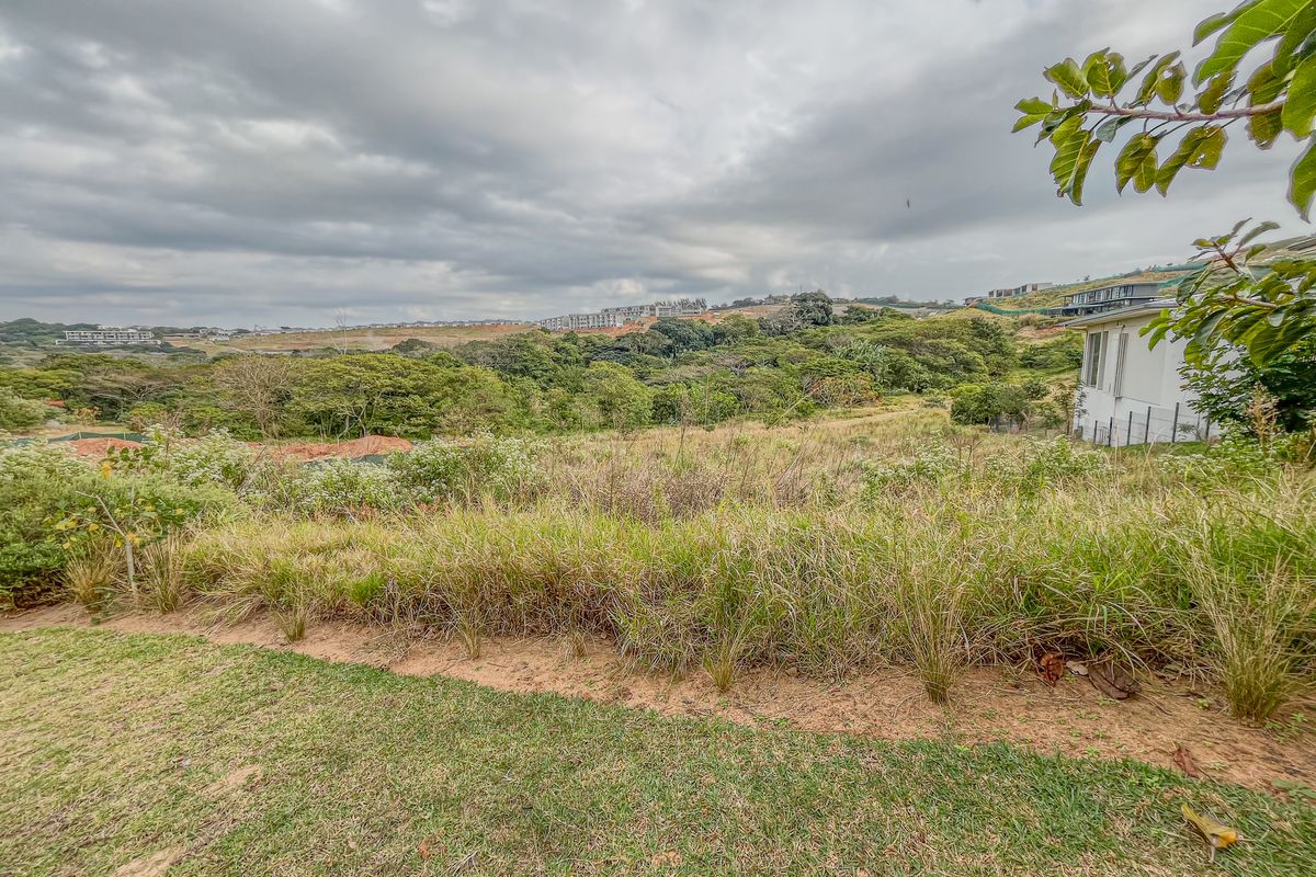 A wide-angle view of the vacant residential land, showcasing the natural sloped terrain and surrounding landscape.