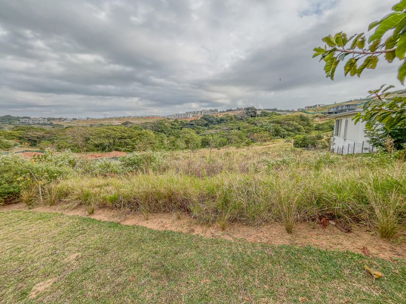A wide-angle view of the vacant residential land, showcasing the natural sloped terrain and surrounding landscape.