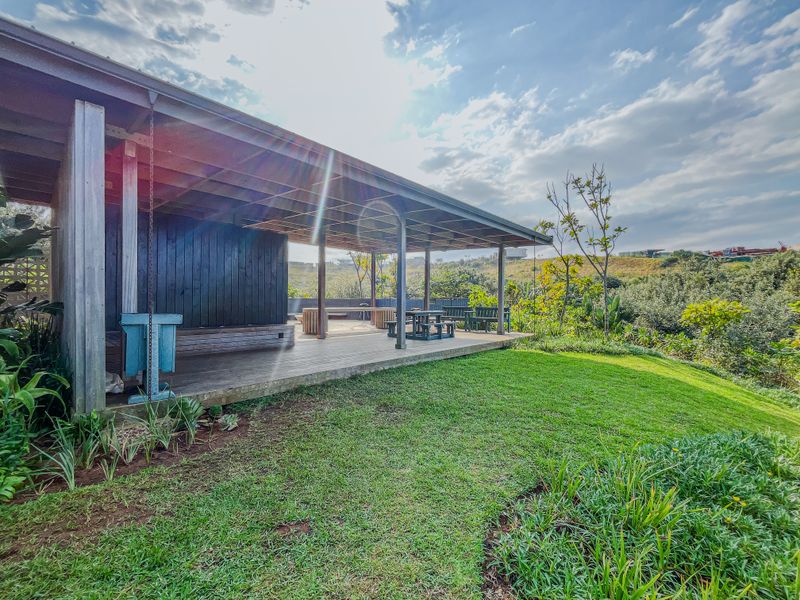 A spacious covered timber deck patio overlooking a landscaped garden and natural surroundings, providing an ideal outdoor entertainment area.