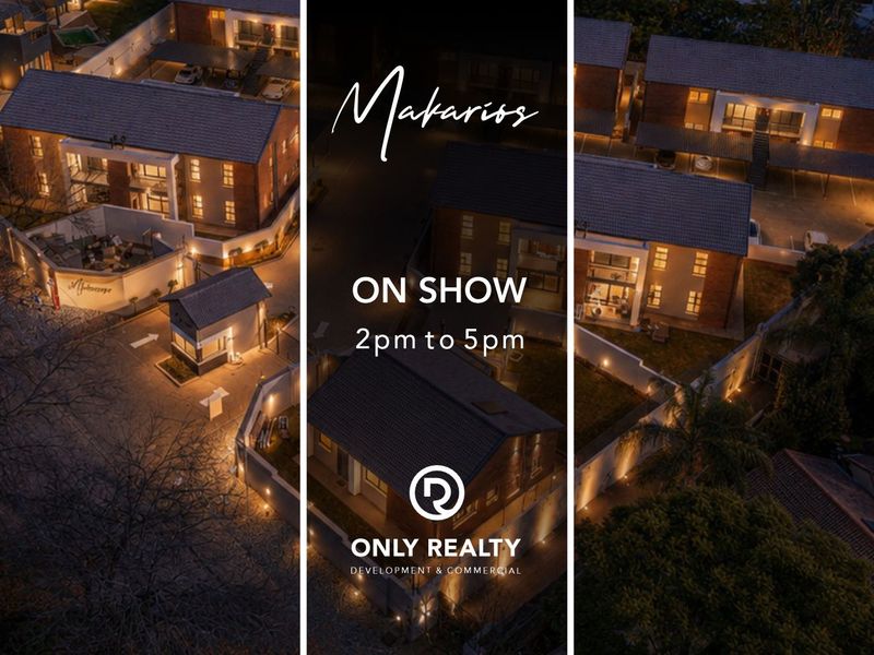 Aerial night view of the apartment complex featuring a secure entrance gatehouse, paved driveway, and exterior building lighting.