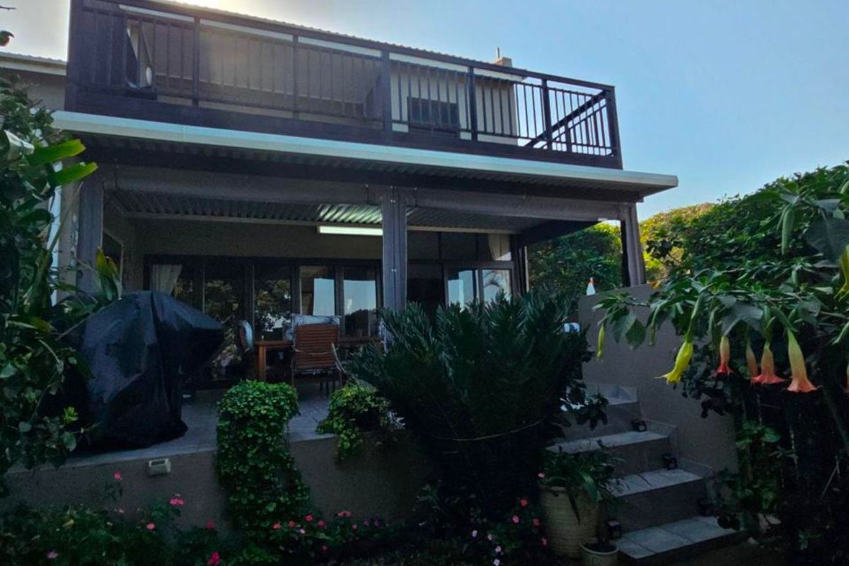 Rear view of the townhouse featuring a covered patio area on the ground level and a balcony on the upper level with metal railings.