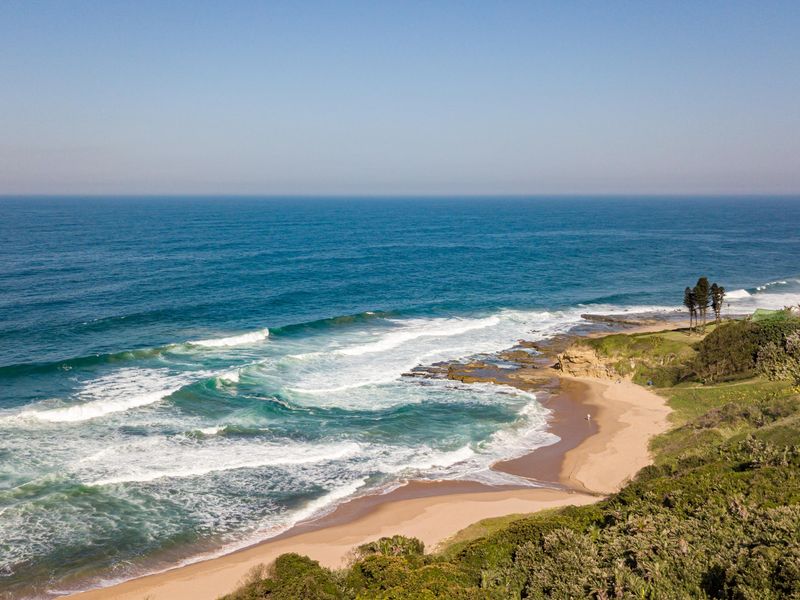 An elevated aerial view of the pristine coastline, featuring sandy beaches and ocean waves, highlighting the natural beauty of the property's surroundings.