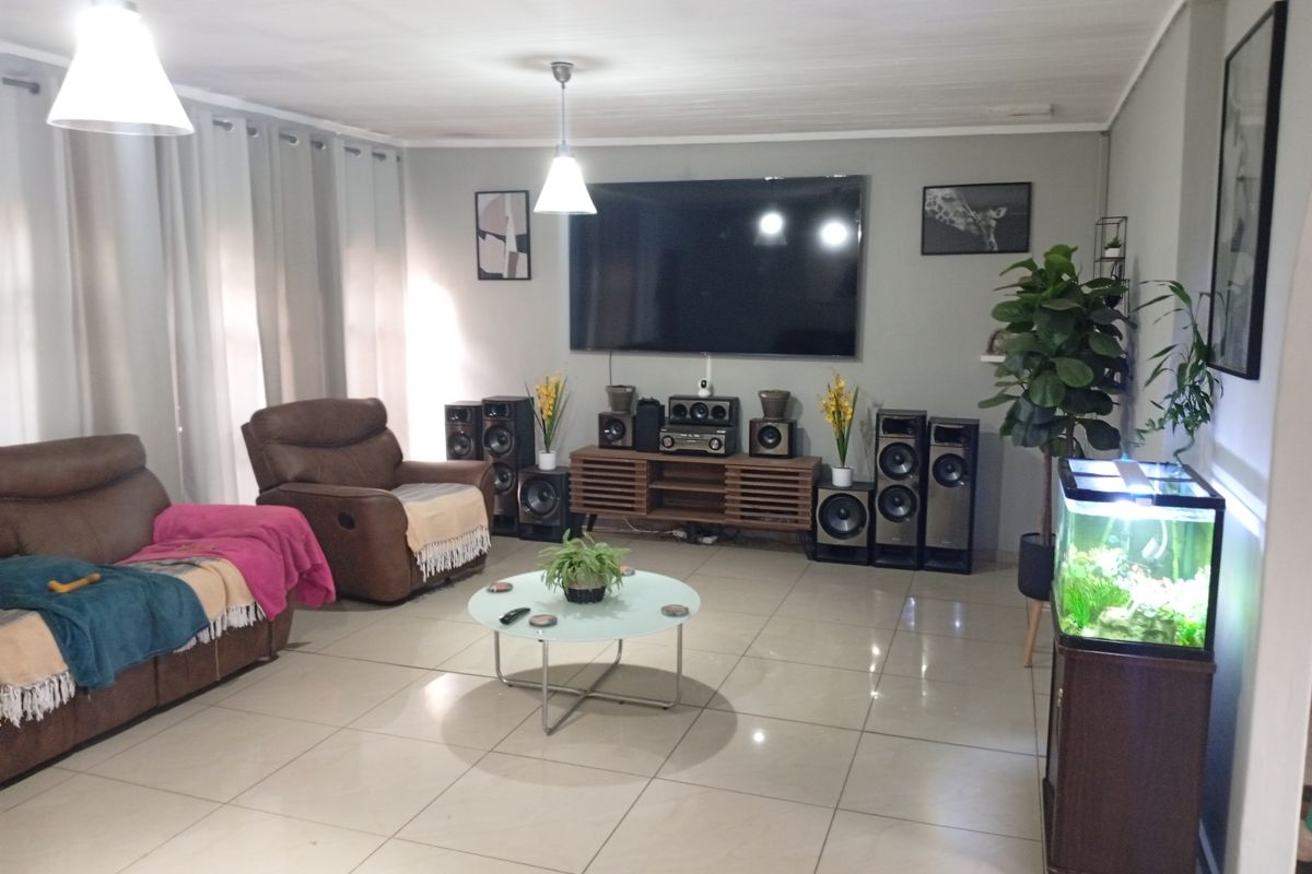 Spacious living room featuring large format floor tiles, neutral wall finishes, and recessed lighting, providing a comfortable and well-maintained area for relaxation.
