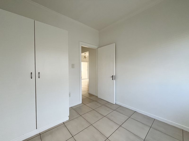 An empty bedroom featuring neutral tiled flooring and a built-in wardrobe, offering a clean and versatile space ready for personalization.