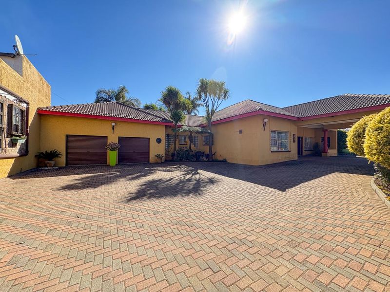 Front exterior view of a single-story house featuring a paved driveway, double garage, and a covered entrance area under a tiled roof.