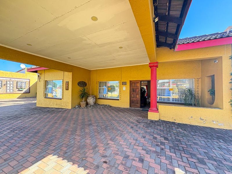 Front entrance area featuring a paved driveway, covered porch with decorative column, and secure window fixtures.