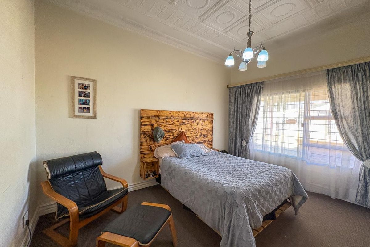 A bedroom featuring a classic pressed metal ceiling, neutral walls, and a large window allowing natural light.