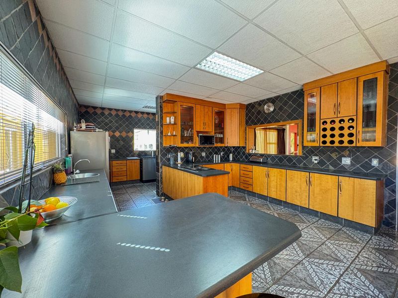 Spacious kitchen featuring extensive wooden cabinetry, dark laminate countertops, tiled backsplash, and functional layout with integrated wine storage.
