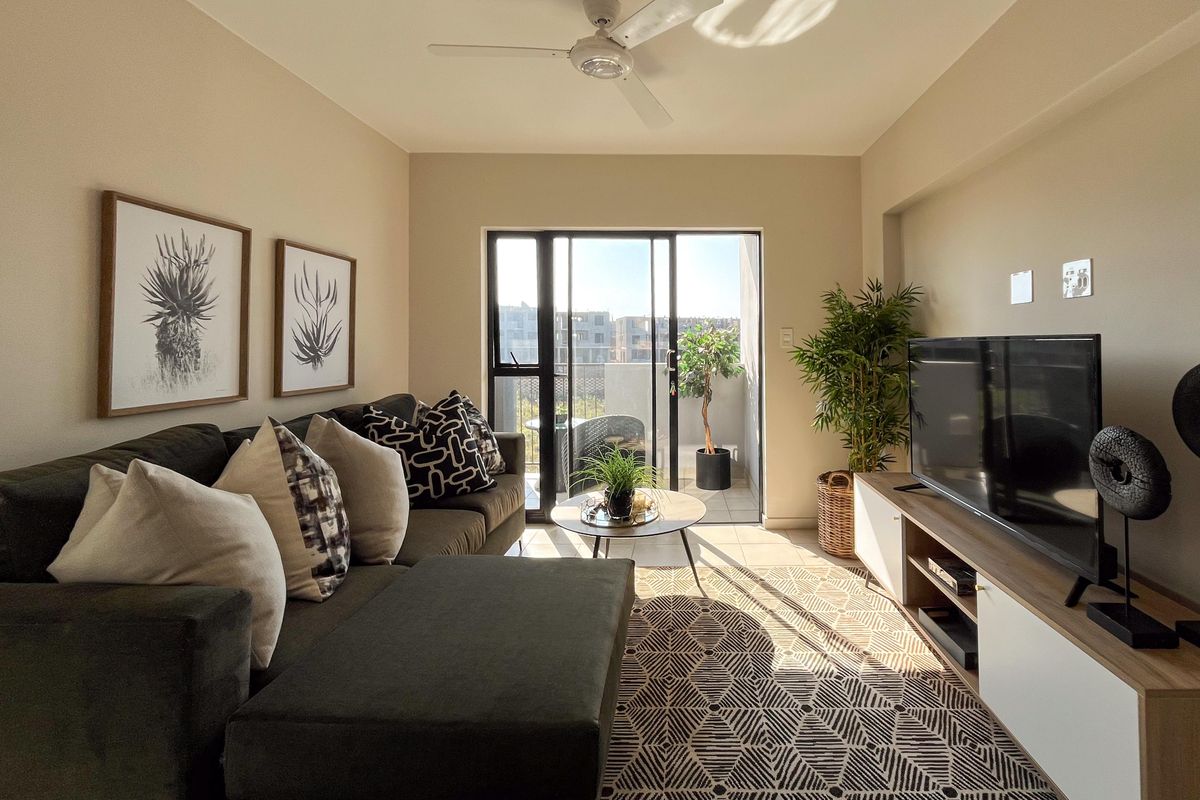 A well-maintained living room featuring a ceiling fan and large sliding glass doors that provide access to an outdoor balcony area.