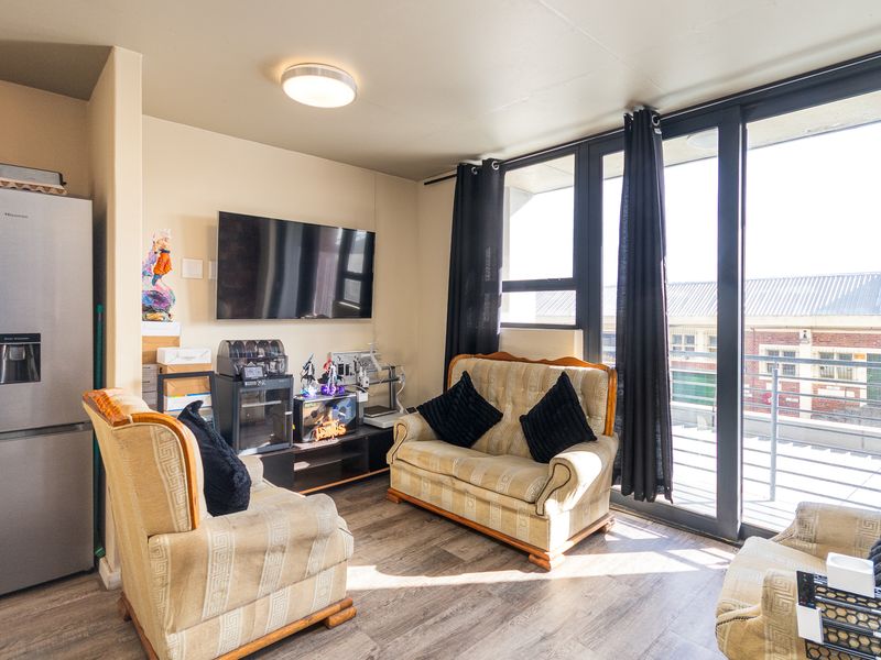 Open plan living area featuring laminate flooring and large sliding glass doors providing access to an outdoor balcony space.