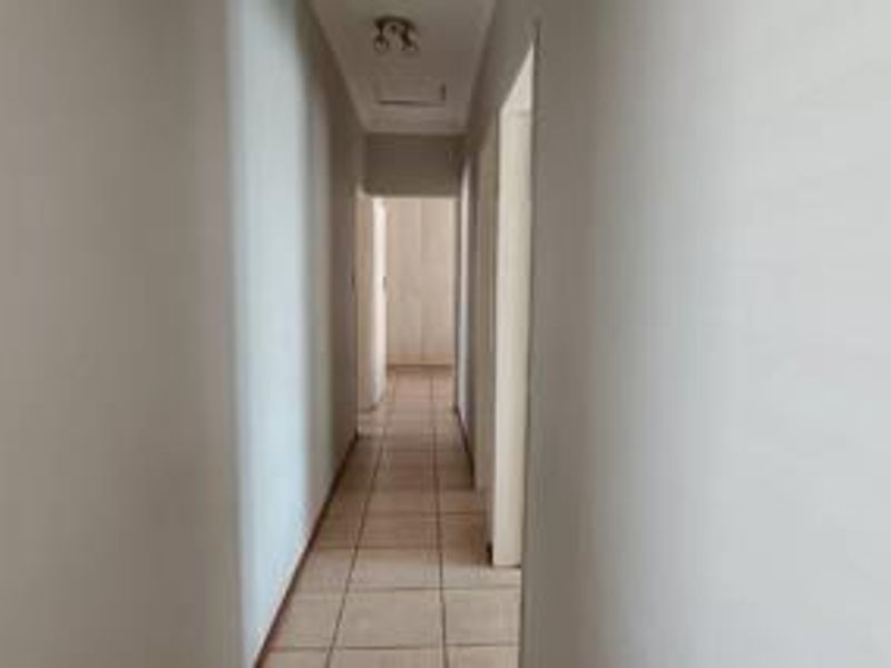 A simple, empty interior hallway featuring neutral wall finishes and tiled flooring, providing access to various rooms within the townhouse.