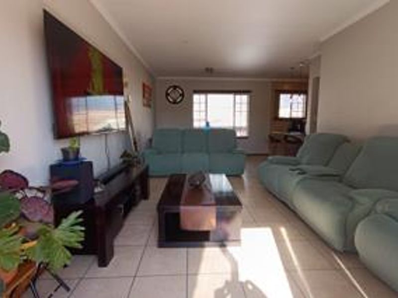 A spacious living room featuring neutral tiled flooring and coved ceilings, offering a comfortable and functional layout for relaxation.