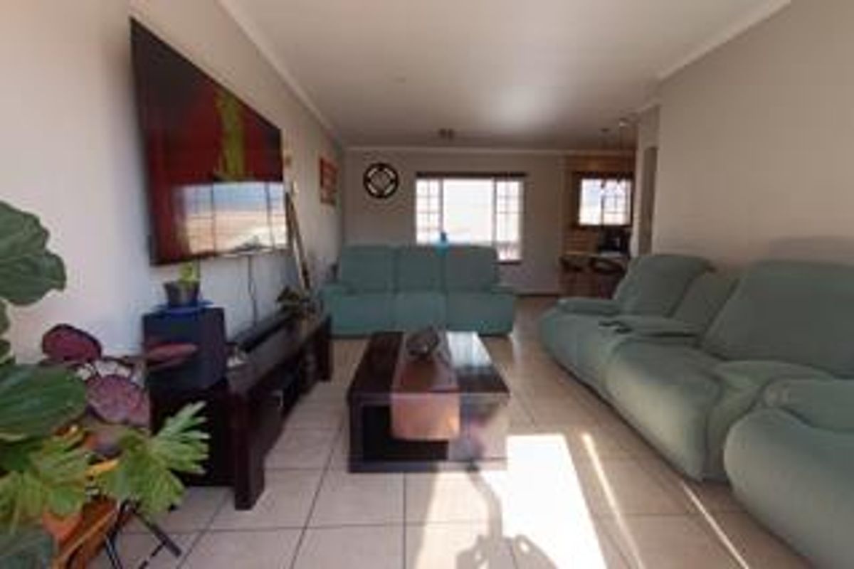 A spacious living room featuring neutral tiled flooring and coved ceilings, offering a comfortable and functional layout for relaxation.