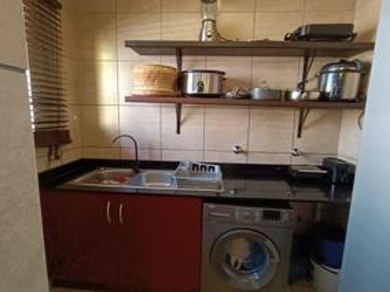A functional scullery area featuring a double sink, black granite countertops, built-in cabinetry, and open shelving for additional storage.