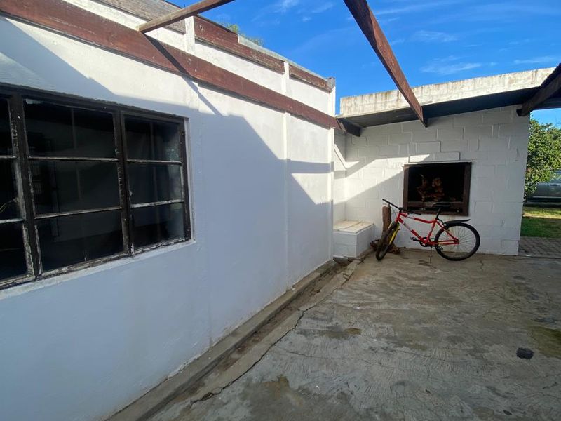 Outdoor patio area featuring a built-in braai, concrete flooring, and a timber pergola structure, offering potential for an upgraded entertainment space.