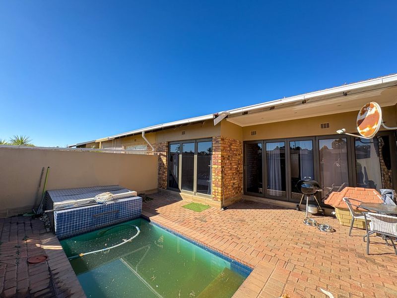 Rear patio area featuring a small swimming pool, brick paving, and direct access to the interior through sliding glass doors.