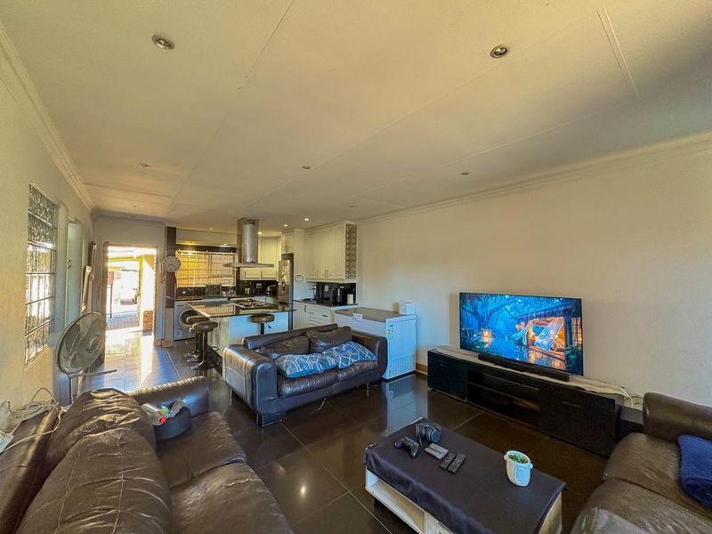 Open-plan living and kitchen area featuring tiled flooring, recessed lighting, and a central kitchen island with an extractor fan.