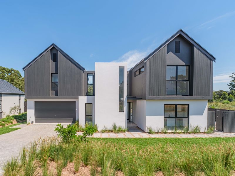 Modern two-story residential home featuring a striking combination of white render and dark vertical cladding, complete with a double garage and paved driveway.