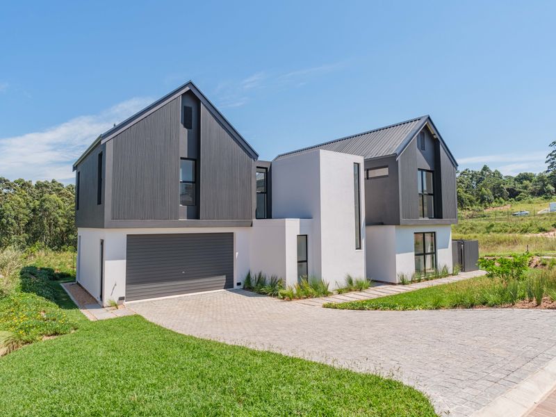 Modern double-story residence featuring a striking combination of dark corrugated metal cladding and white render, complete with a paved driveway and integrated garage.