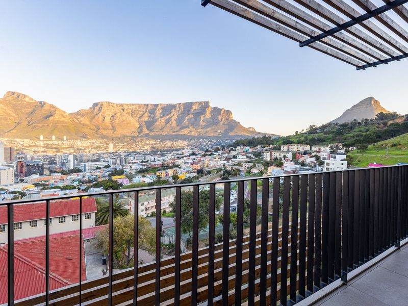 A modern balcony featuring a sleek metal balustrade and timber pergola, offering expansive panoramic views of the city and Table Mountain.