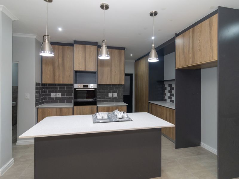 Modern kitchen featuring a central island, built-in oven, stone countertops, and contemporary cabinetry with stylish pendant lighting.