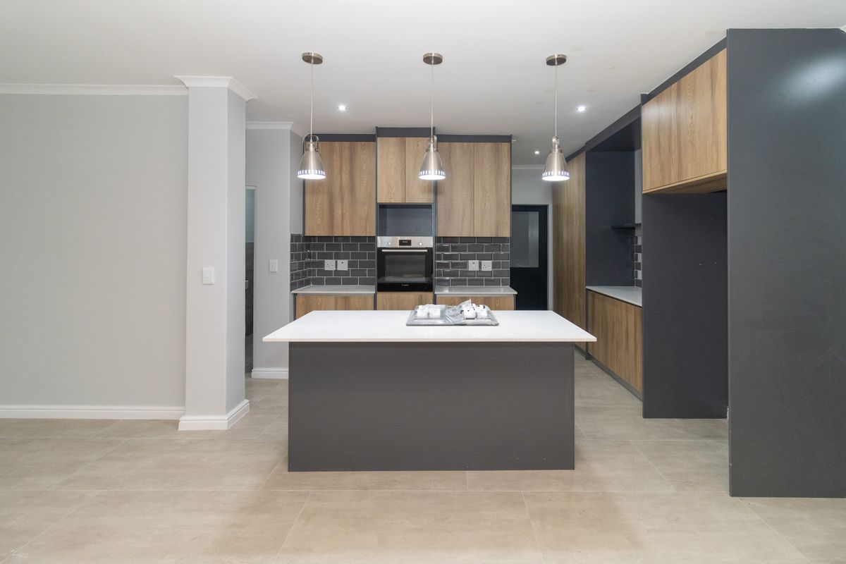 Modern kitchen featuring a central island, built-in oven, stone countertops, and contemporary two-tone cabinetry with a stylish subway tile backsplash.