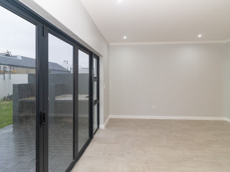 Bright open-plan living area featuring modern tiled flooring, recessed downlights, and large aluminium stacker doors providing seamless access to the outdoor patio.