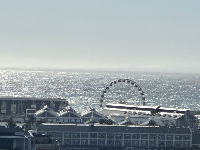 An elevated view overlooking the ocean and a coastal entertainment area featuring a ferris wheel.