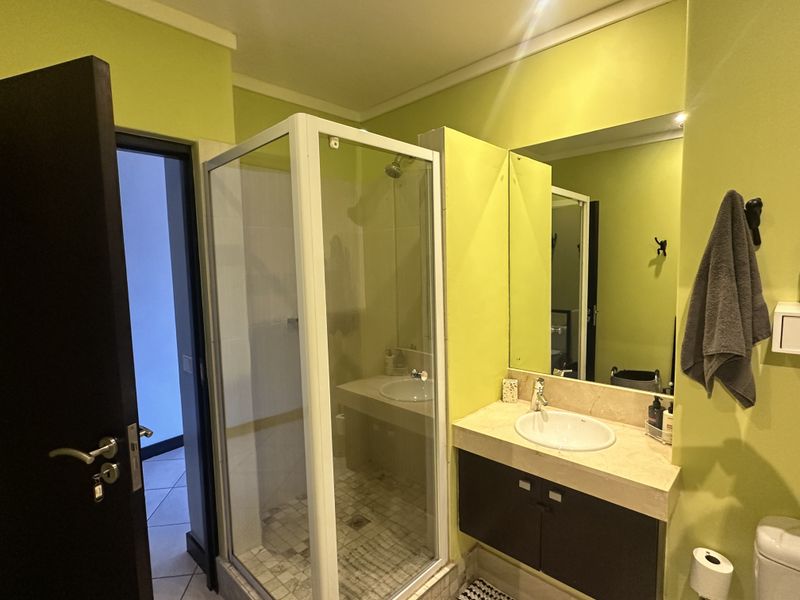A functional bathroom featuring a shower enclosure, a vanity with a stone countertop, and a wall-mounted mirror.