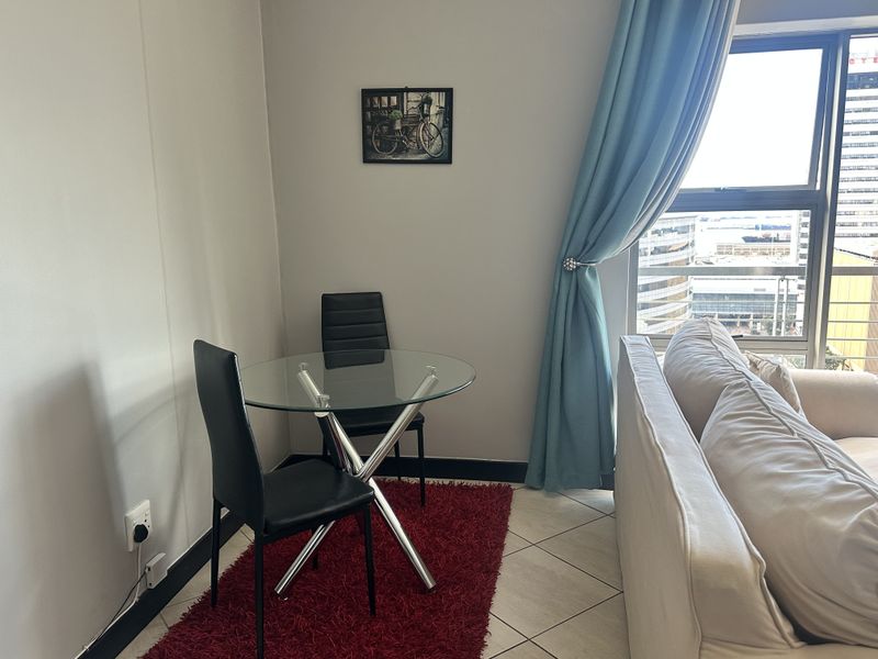 A living area featuring tiled flooring and a large window providing natural light and urban views.