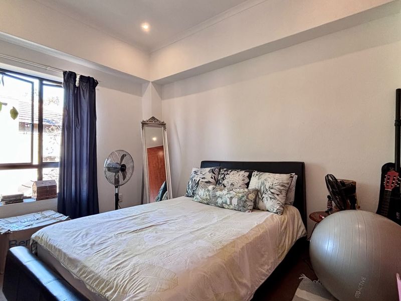 A bedroom featuring a built-in wardrobe, recessed downlighting, and a window with natural light.