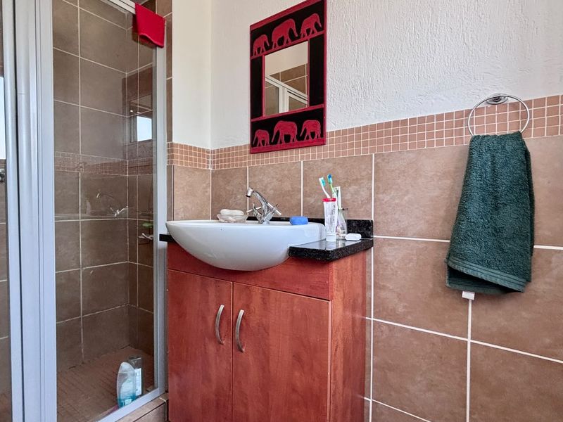 A functional bathroom featuring a shower enclosure, a vanity cabinet with a basin, and tiled wall finishes.