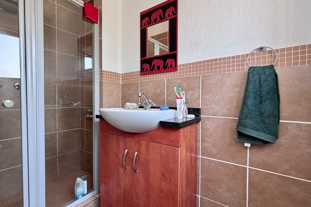 A functional bathroom featuring a shower enclosure, a vanity cabinet with a basin, and tiled wall finishes.