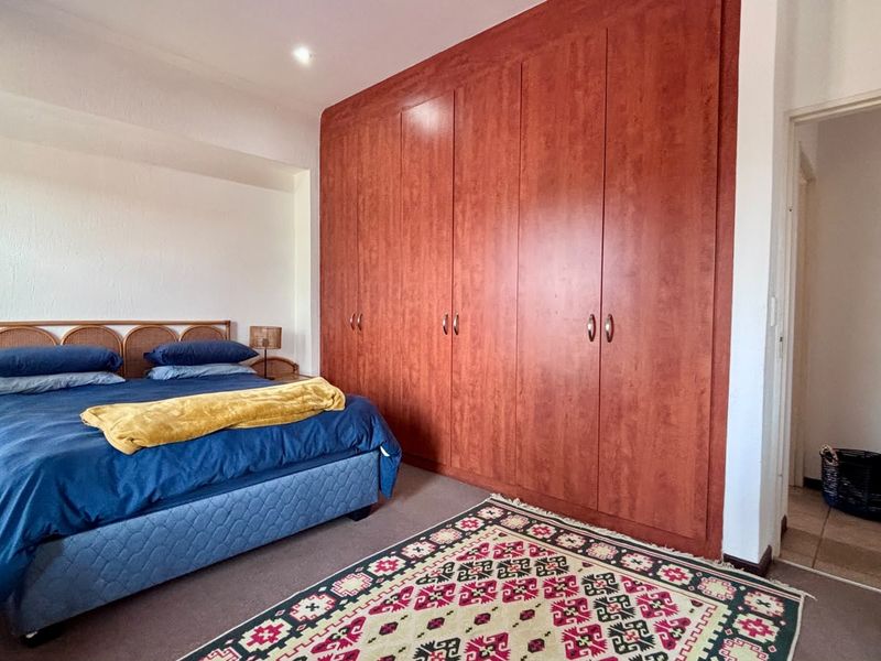 A bedroom featuring extensive floor-to-ceiling built-in wooden cupboards and recessed ceiling lighting, providing ample storage space.