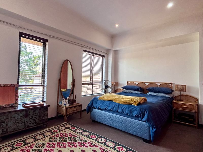 A well-lit bedroom featuring built-in wardrobes, recessed ceiling lighting, and large windows with venetian blinds, offering a comfortable and functional living space.