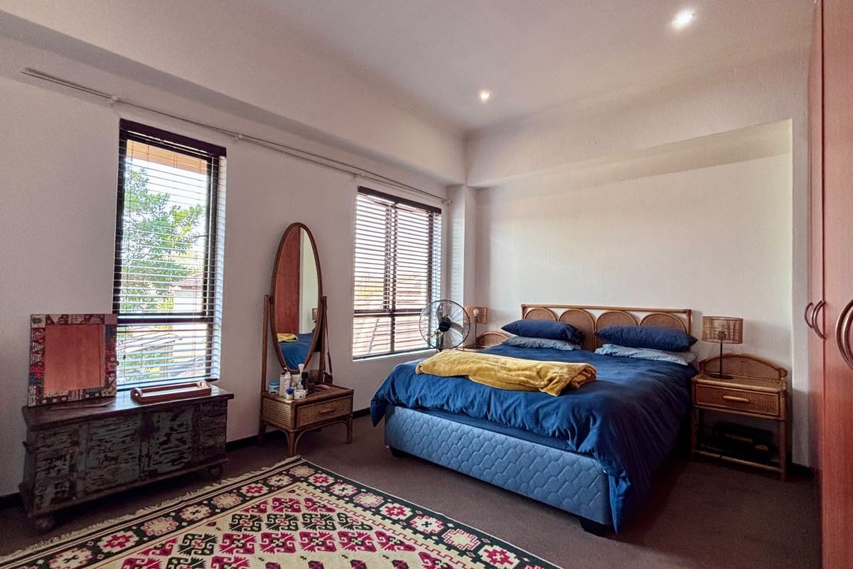 A well-lit bedroom featuring built-in wardrobes, recessed ceiling lighting, and large windows with venetian blinds, offering a comfortable and functional living space.