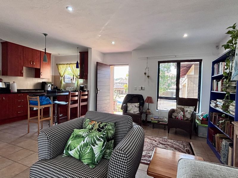 Open-plan living area featuring a kitchen with red cabinetry, granite countertops, and tiled flooring, seamlessly connected to a comfortable lounge space.