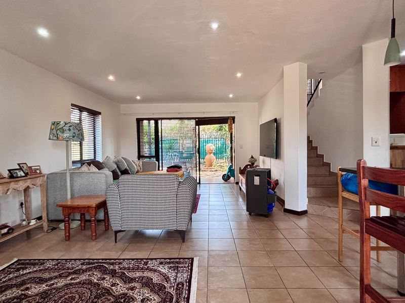 Spacious open-plan living area featuring tiled flooring, recessed lighting, and a sliding door providing direct access to the rear garden.