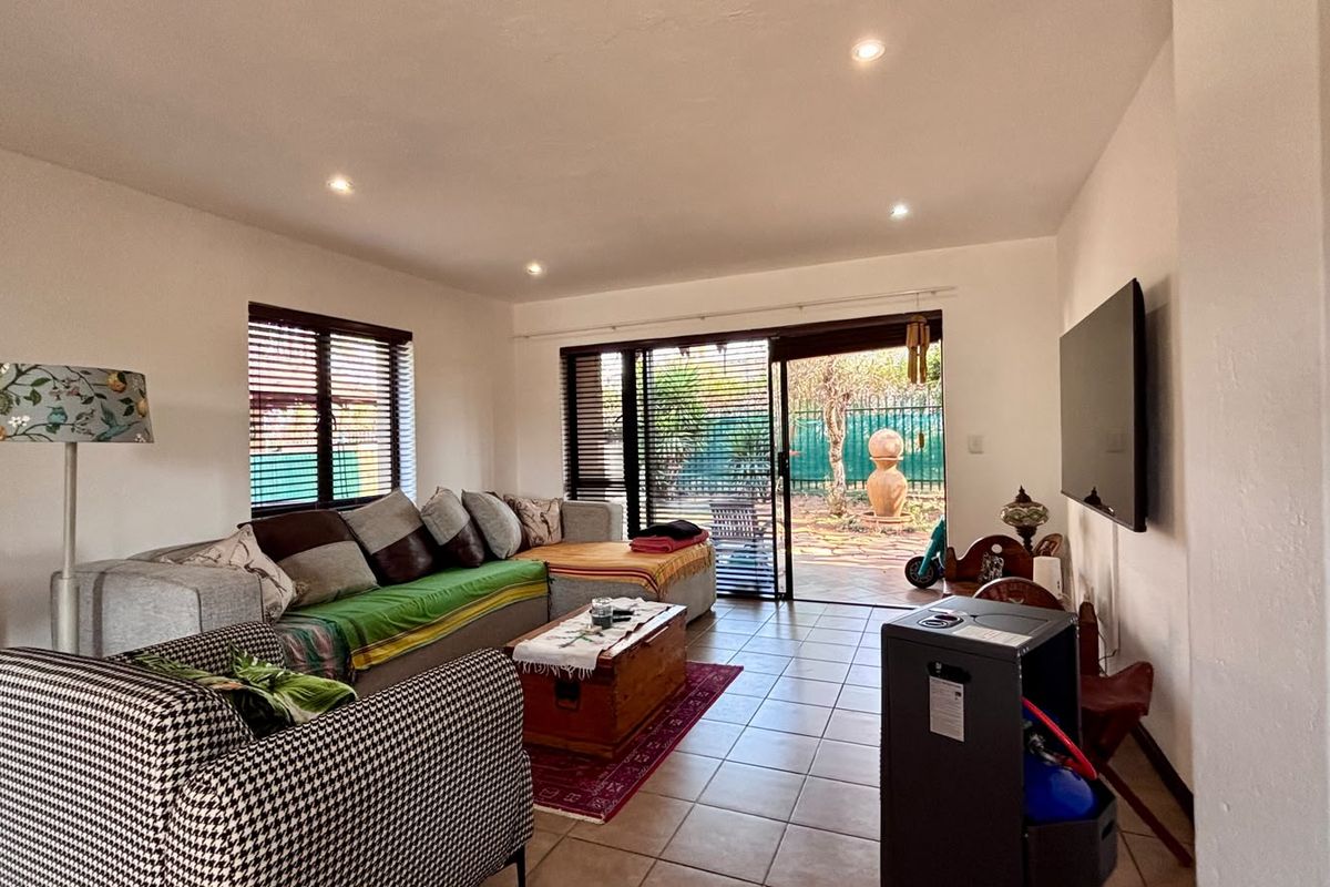 A living room featuring tiled flooring, recessed lighting, and large sliding glass doors that provide direct access to the outdoor patio area.