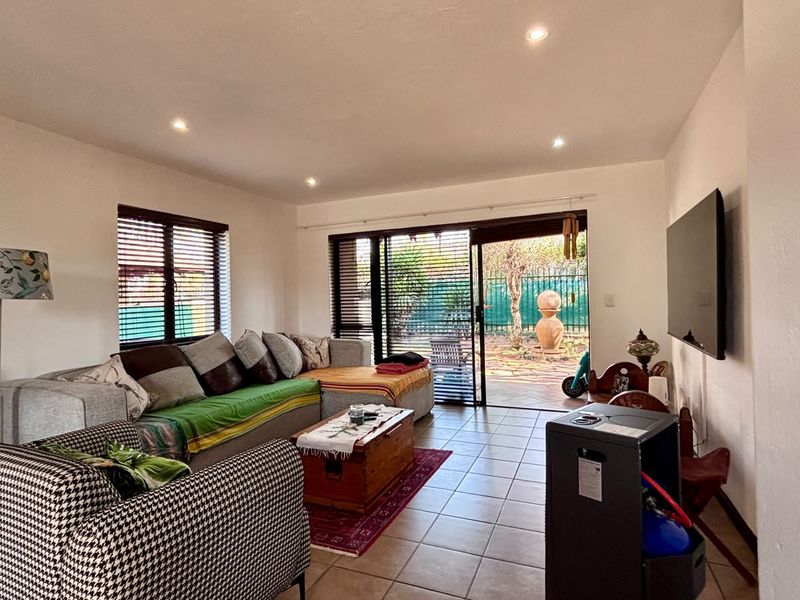 A living room featuring tiled flooring, recessed lighting, and large sliding glass doors that provide direct access to the outdoor patio area.