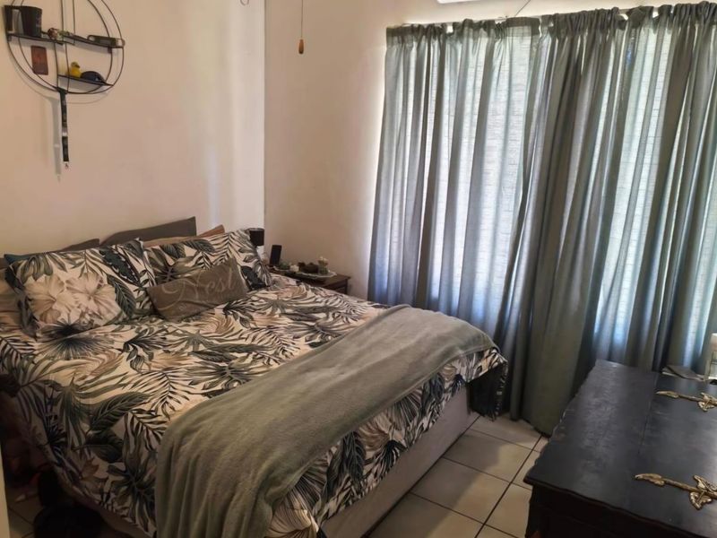 A functional bedroom featuring tiled flooring and window treatments, offering a neutral base for personalization.