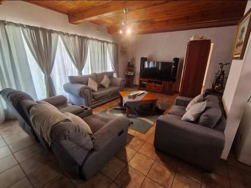 Spacious living room featuring exposed timber ceiling beams and ceramic floor tiles, offering a warm and traditional aesthetic.