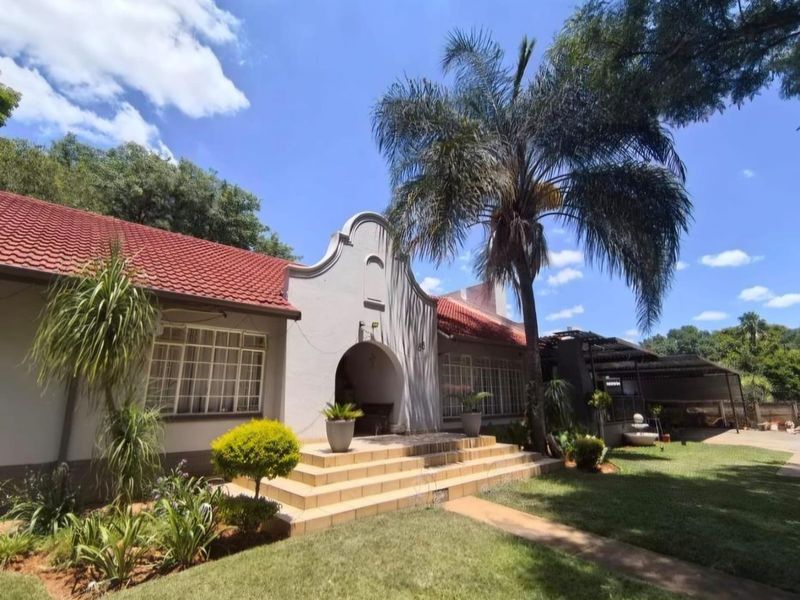 Front elevation of a traditional house featuring a distinctive arched entrance, tiled roof, and landscaped front garden with a paved walkway.